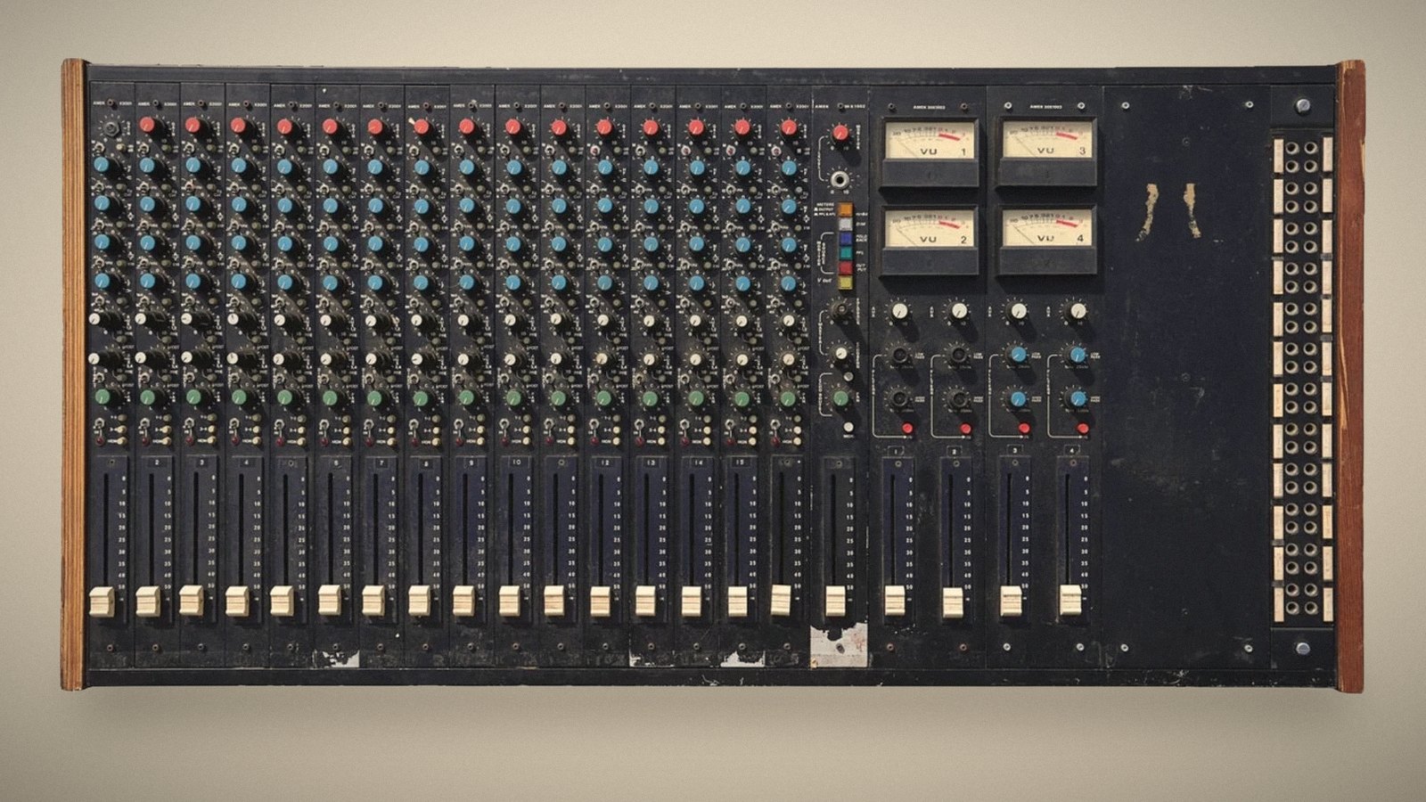 Prince’s AMEK console, front view: 16 channel strips with red, blue and green knobs, four VU meters and a patchbay, in a dark-stained wooden frame